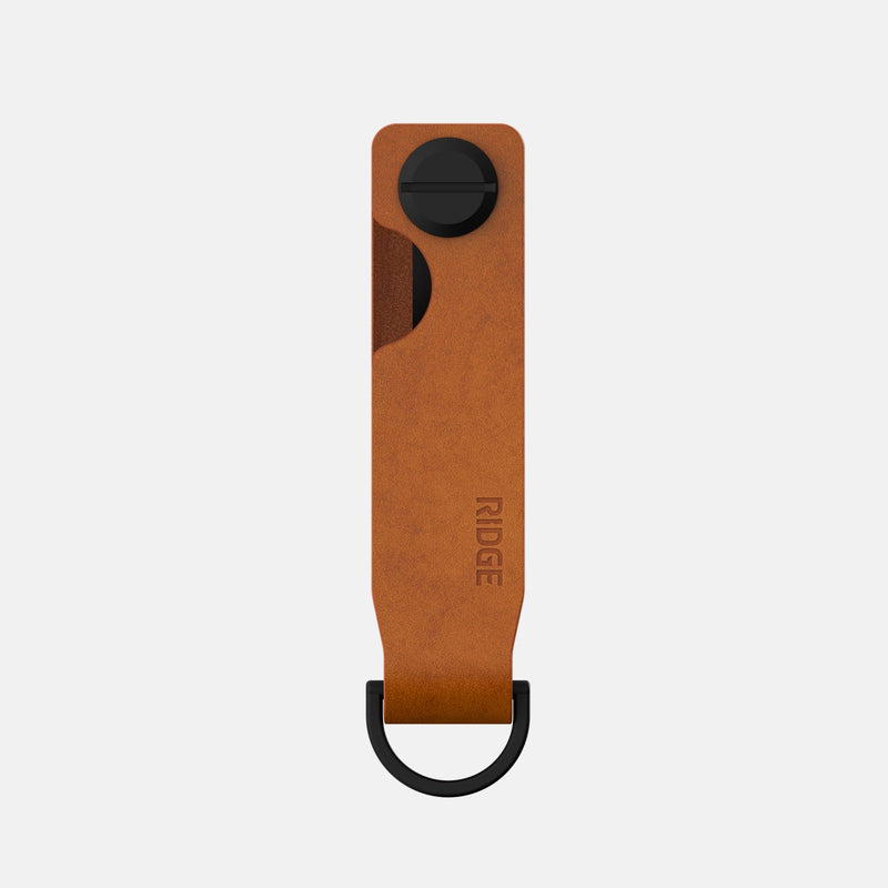 KeyCase in tobacco brown leather, front view, showing Ridge logo stamp and black metal loop and screw.